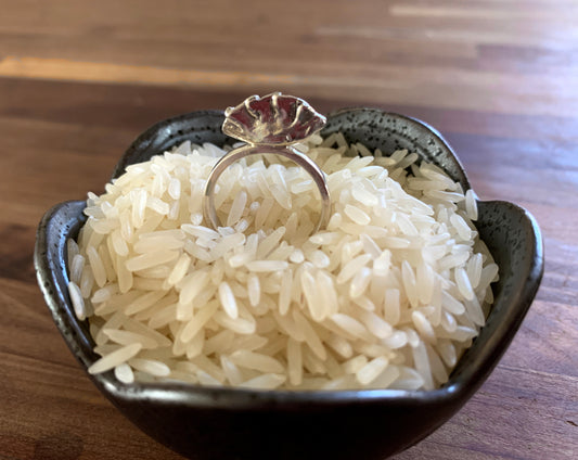 sterling silver dumpling ring sitting in a small bowl of rice