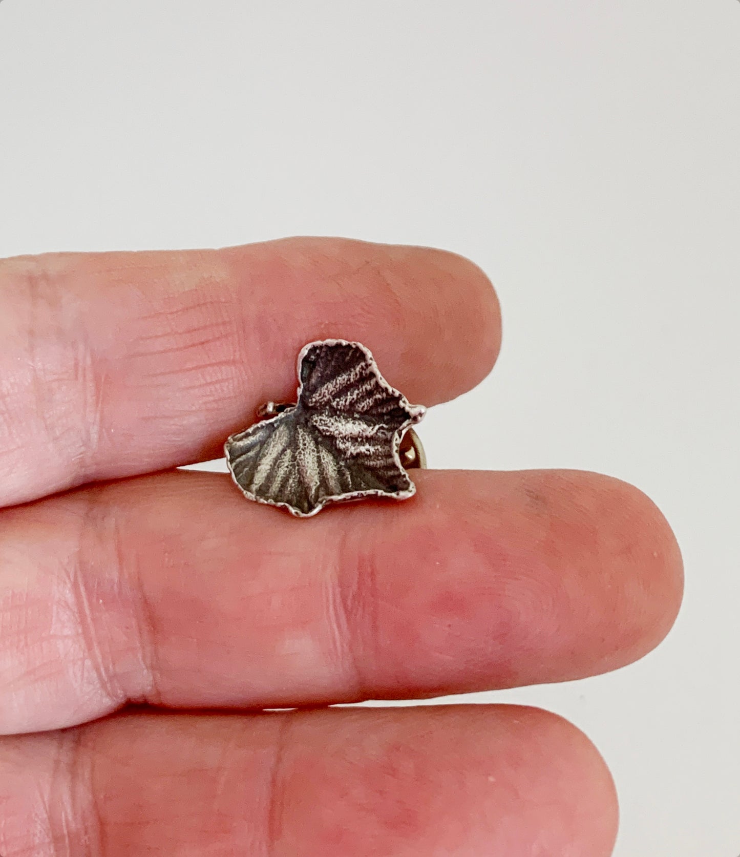 sterling silver grape leaf pin held in a hand